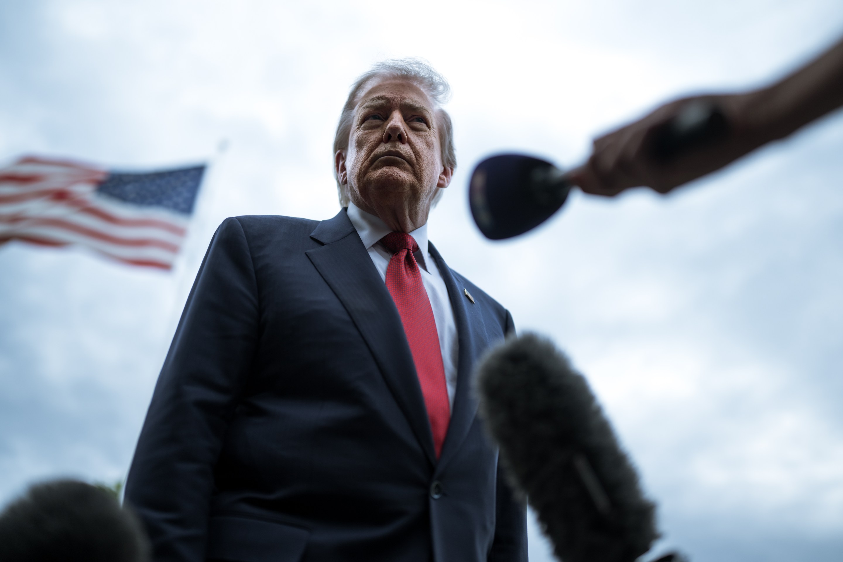 President Donald J. Trump stands behind a microphone and ahead of an American flag